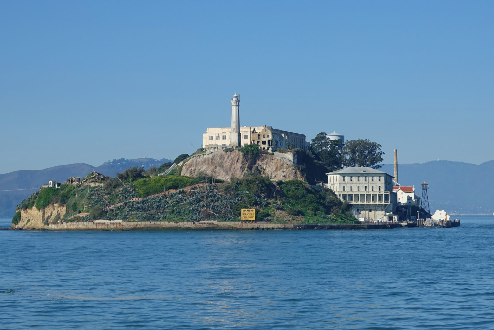 Alcatraz Island crowned with a lighthouse and cellhouse viewed from the Alcatraz Ferry.