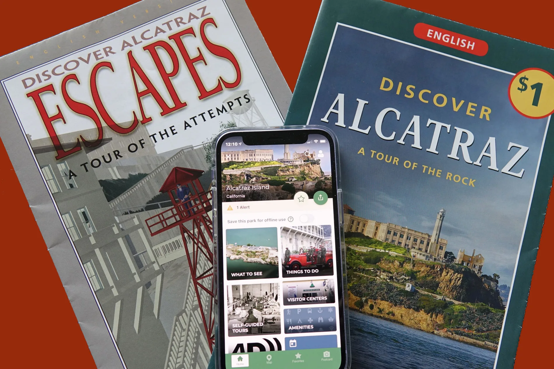 Two Alcatraz tour brochures and a smartphone displaying information on the free National Park Service App.