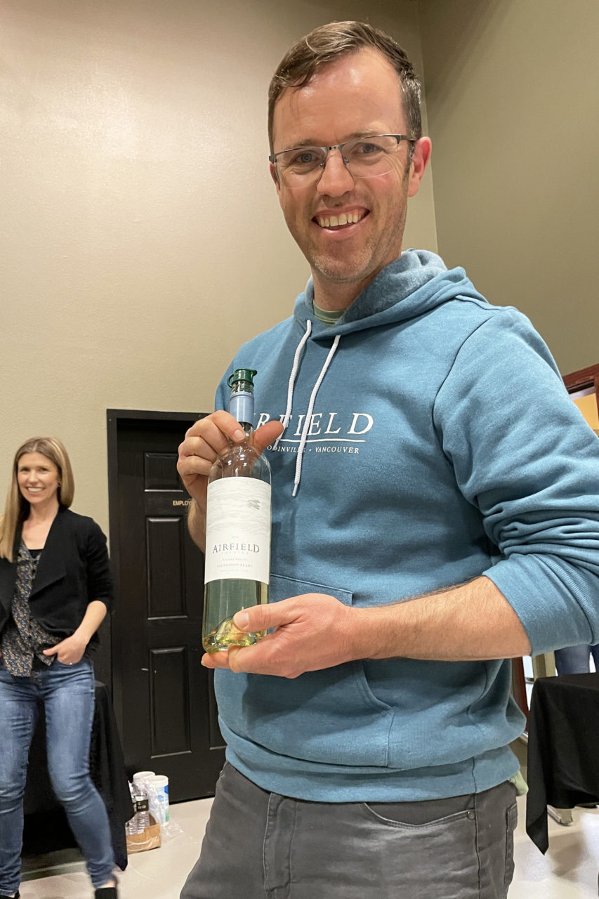 At a winetasting event in Vintner Village, the Airfield Estates winemaker holds a bottle of Sauvignon Blanc.