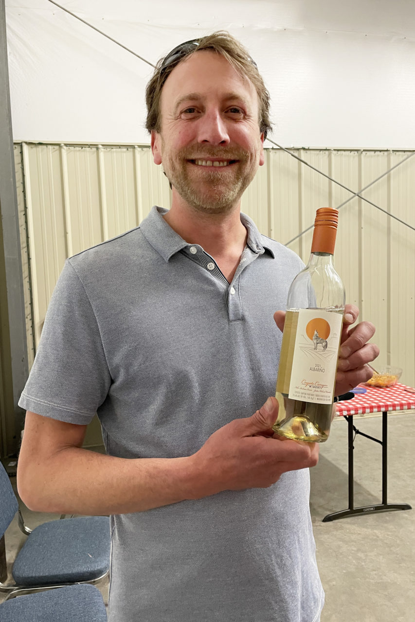 The Coyote Canyon Winery winemaker with a bottle of Albarino at a winetasting event in Vintner Village.