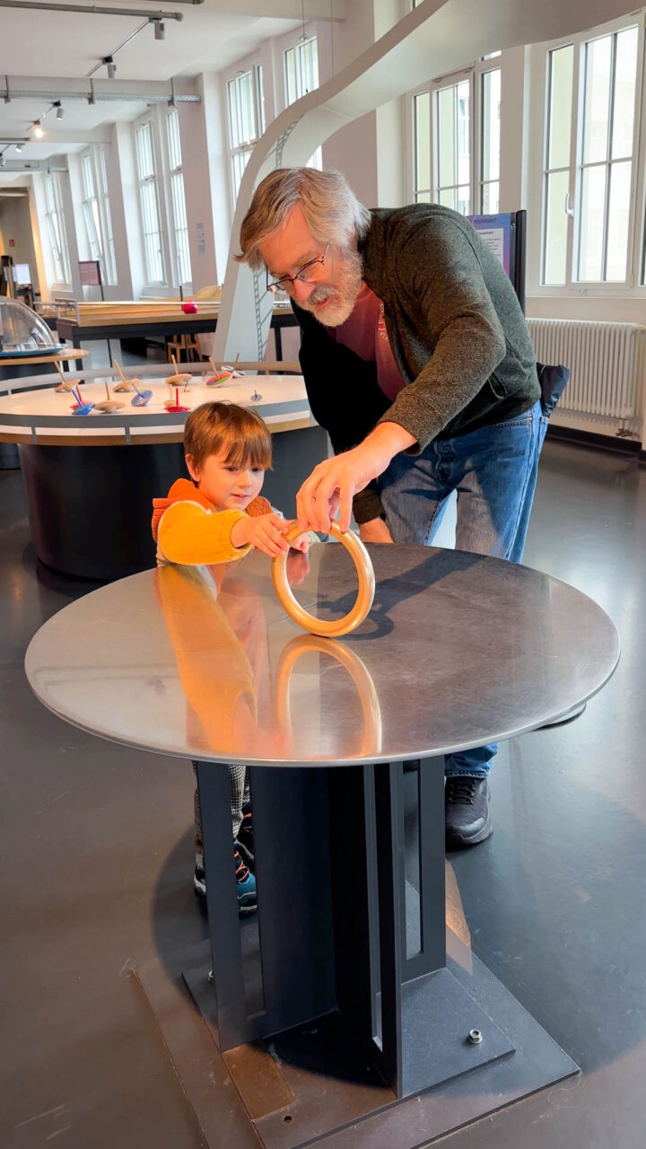 A man and grandson practice spinning a ring at the Dynamikum.